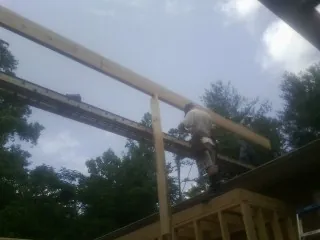 Carpenter setting a ridge beam over a new addition frame — Ice Dam Removal by Roofing Brothers in Chokio