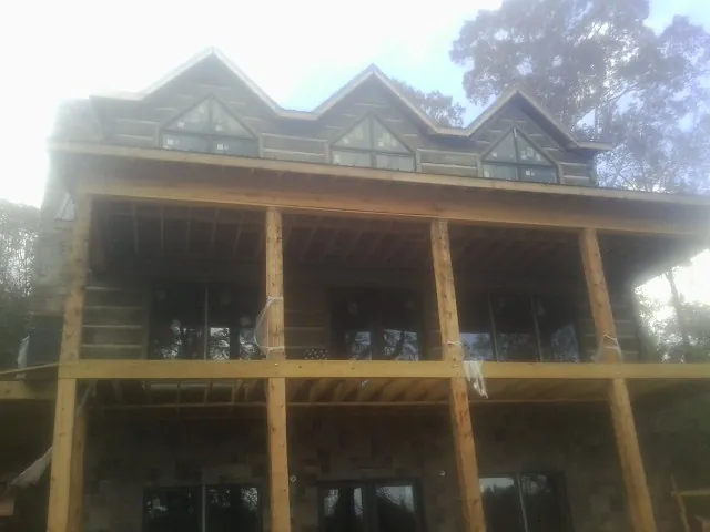 Dormers and porch framing on a large log home under construction — Roof Coating work by our crew in Chokio