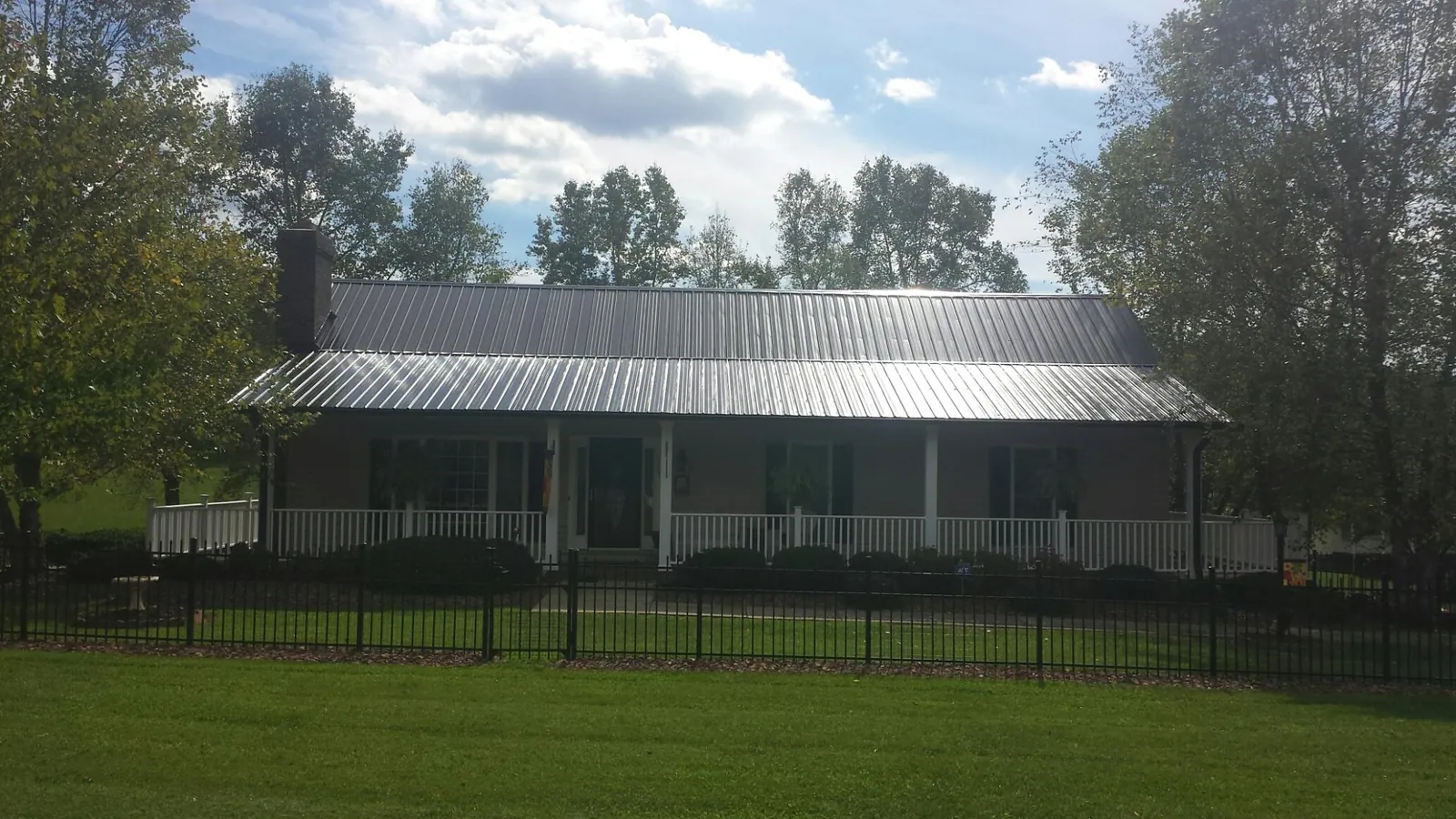 Gray metal roof on a brick ranch with a full width front porch — Gutter Guard Installation work by our crew in Chokio