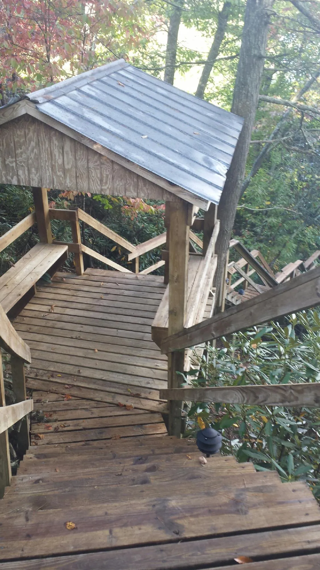 Metal roofed shelter over wooden steps on a wooded walkway — Skylight Repair & Installation work by our crew in Chokio