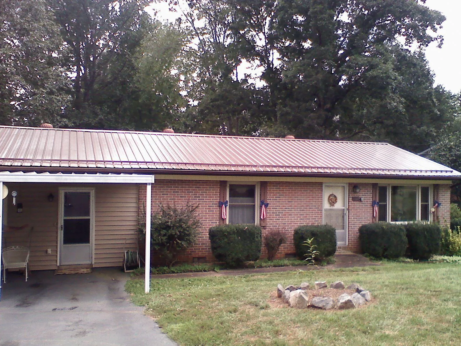Bronze metal roof and carport on a brick ranch home — Roof Repair work by our crew in Chokio