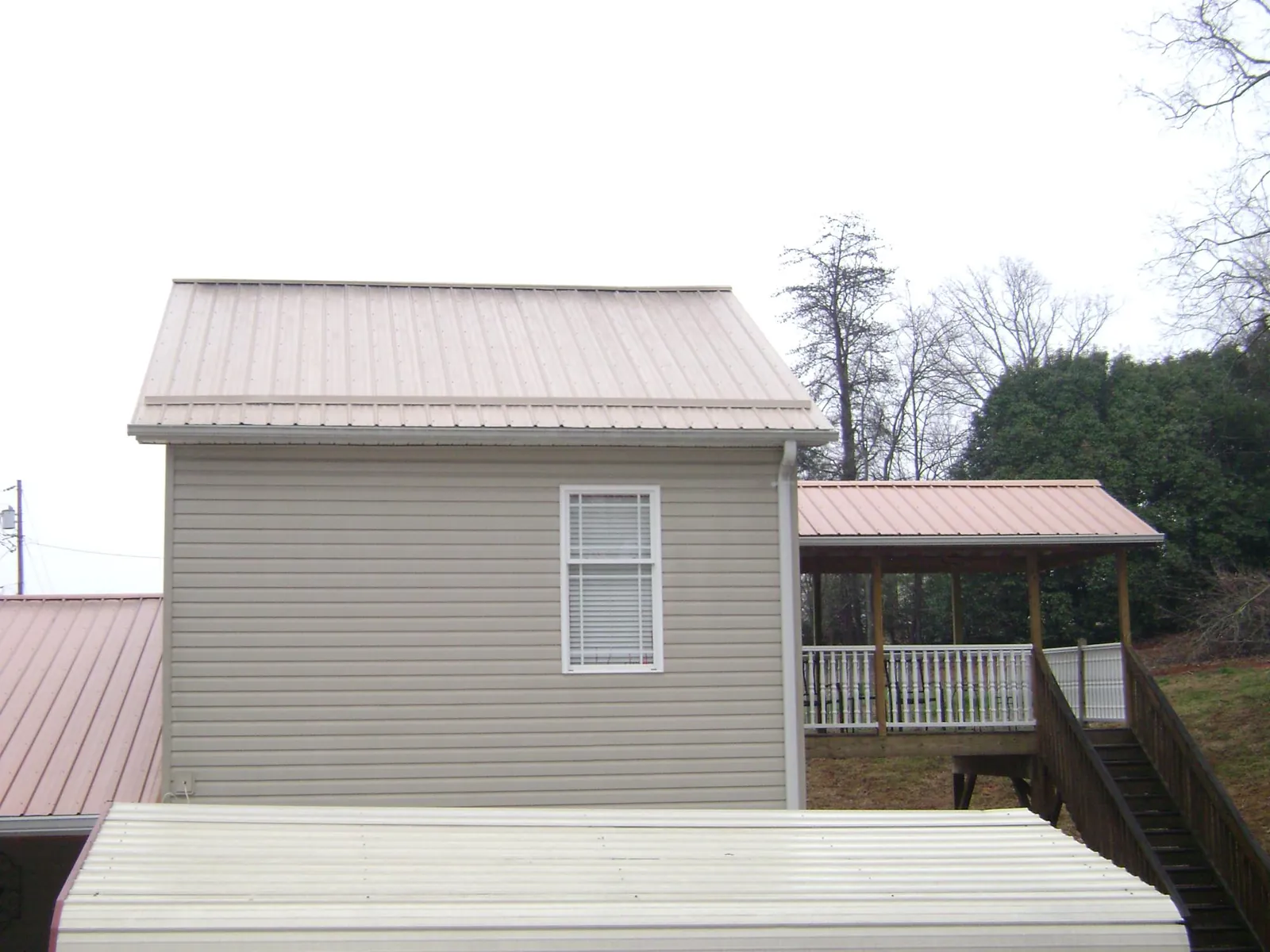 Tan metal roofs on a two story addition and attached porch, from a Roof Replacement job in Chokio